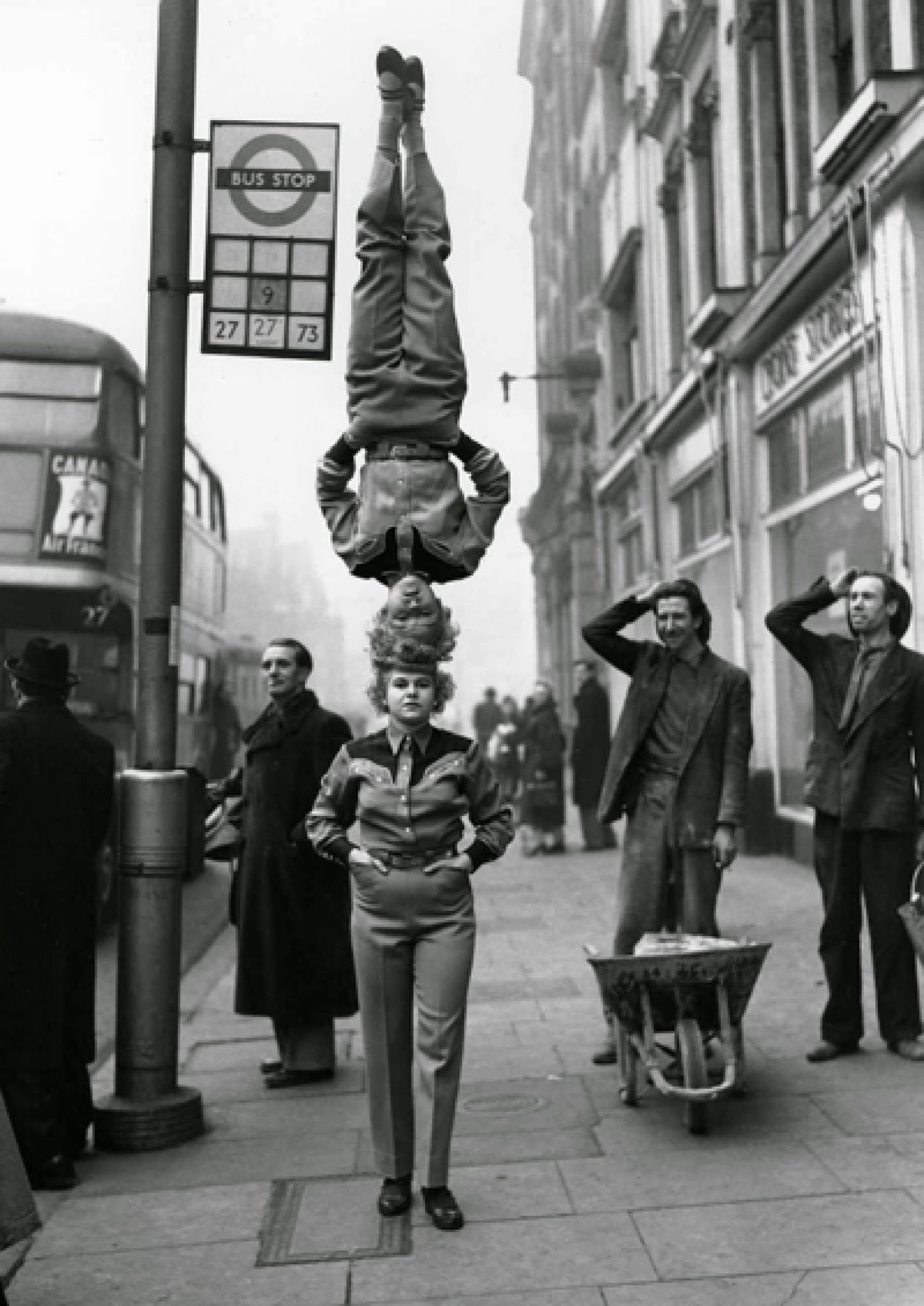 «Two members of the Bertram Mills Circus walk head to head at Hammersmith Broadway in London», 1953